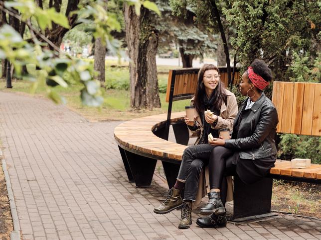 Two young women in eating sandwiches in park