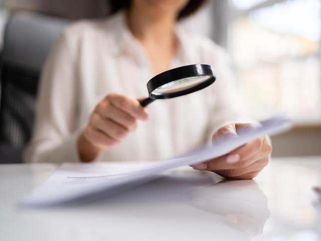 Woman holds magnifying glass over paper