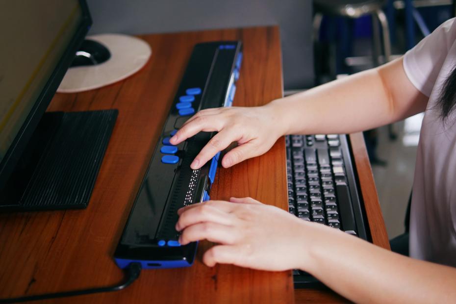 A woman writing using a computer with braille display