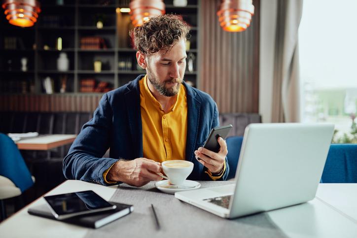 Young male entrepreneur working in a cafe with coffee and laptop