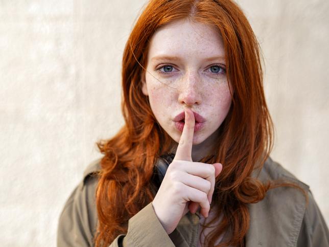 Teen with fingers on lips indicating a quiet space for autistic students