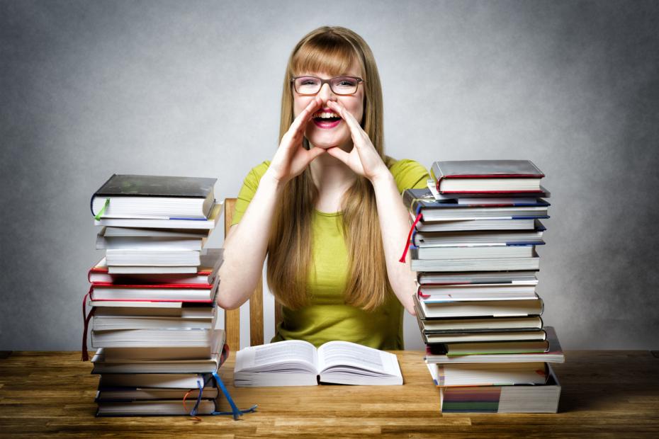 A young woman studying at a desk laden with books