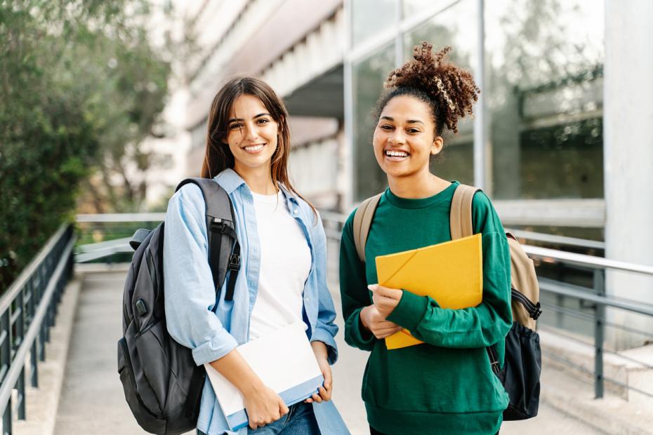 Two students outside campus smiling to camera