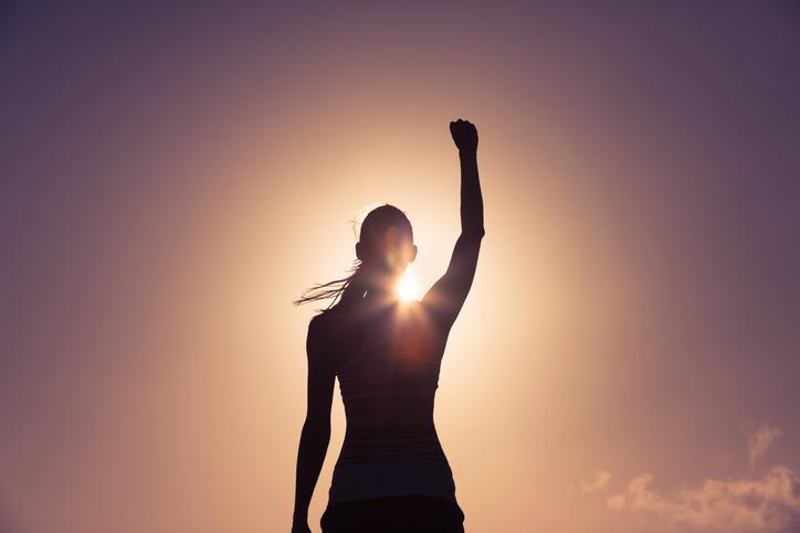 A sihouette of a woman raising her fist in the air