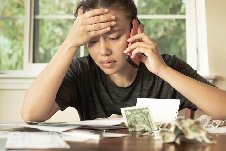 Young woman with US cash and mobile phone, financial difficulty