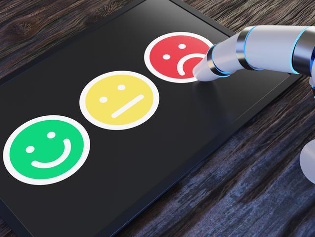 A robot hand takes a survey using emoji faces