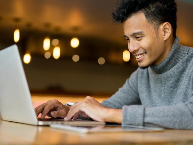 Asian scholar working at laptop, PhD by publication