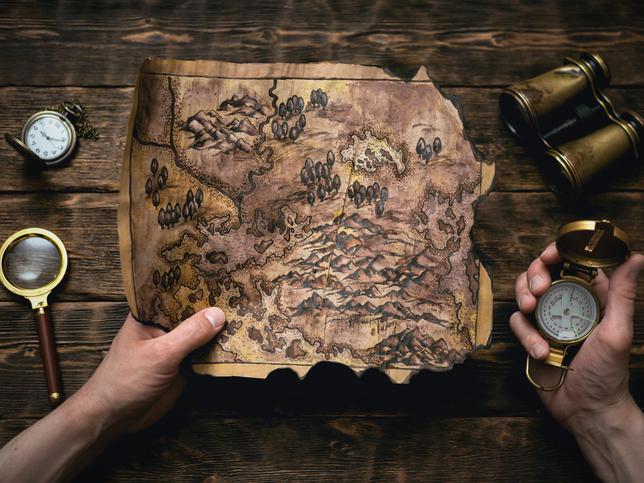 A treasure map, compass and binoculars are laid out on a table