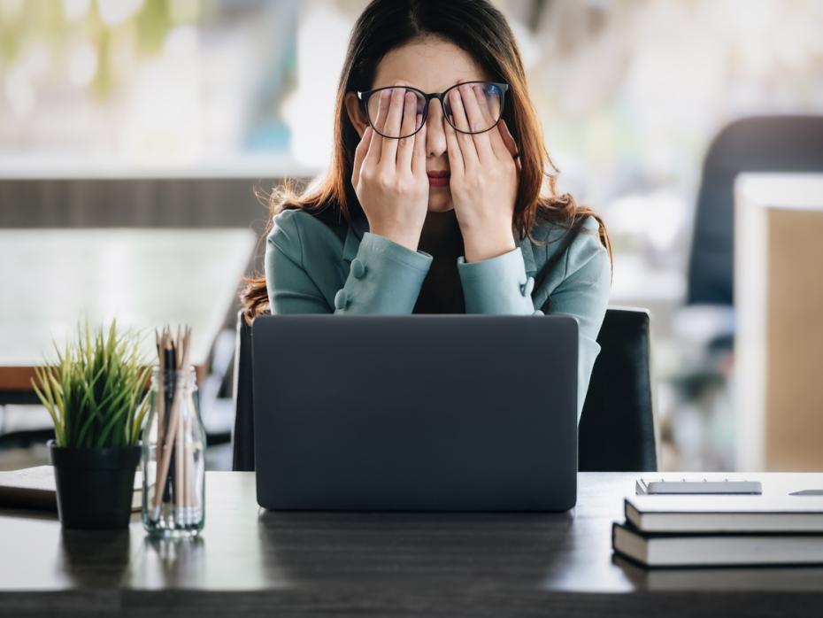 Woman sitting at her laptop with her head in her hands