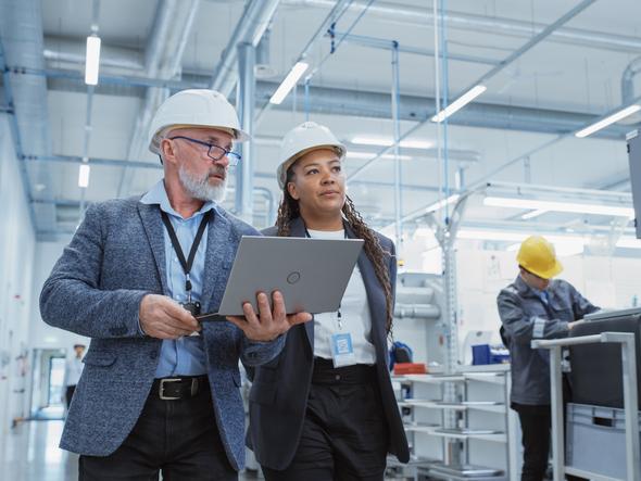 Two people in hard hats walk through a lab