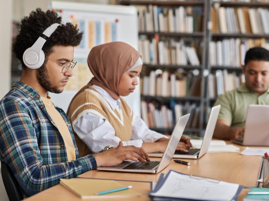 Student sitting at a desk at the library on his laptop