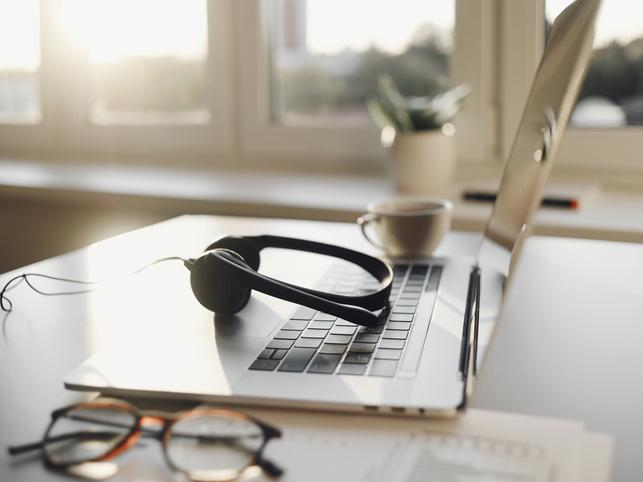 laptop open with headphones and coffee cup