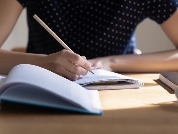 A woman takes notes from an open textbook