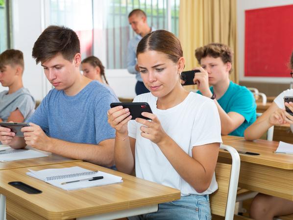 Students in a class look at their phones