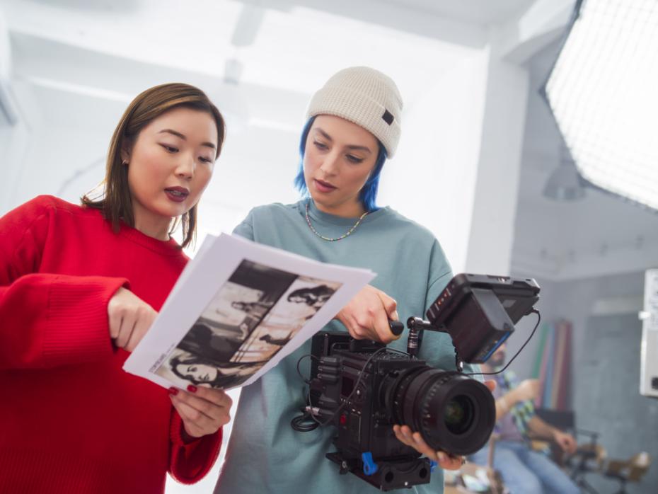 Students working on a film treatment with a camera in hand
