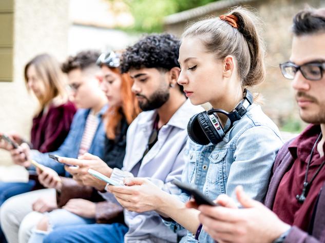 A line of students look at their phones