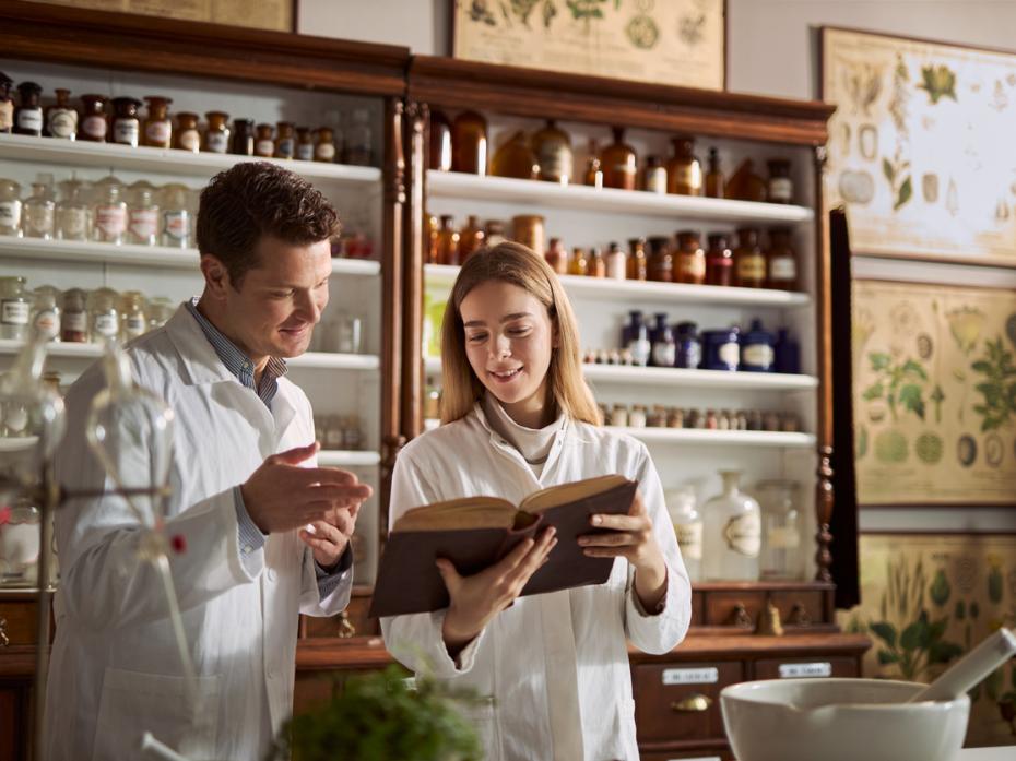 Two chemists in a lab consulting a training manual