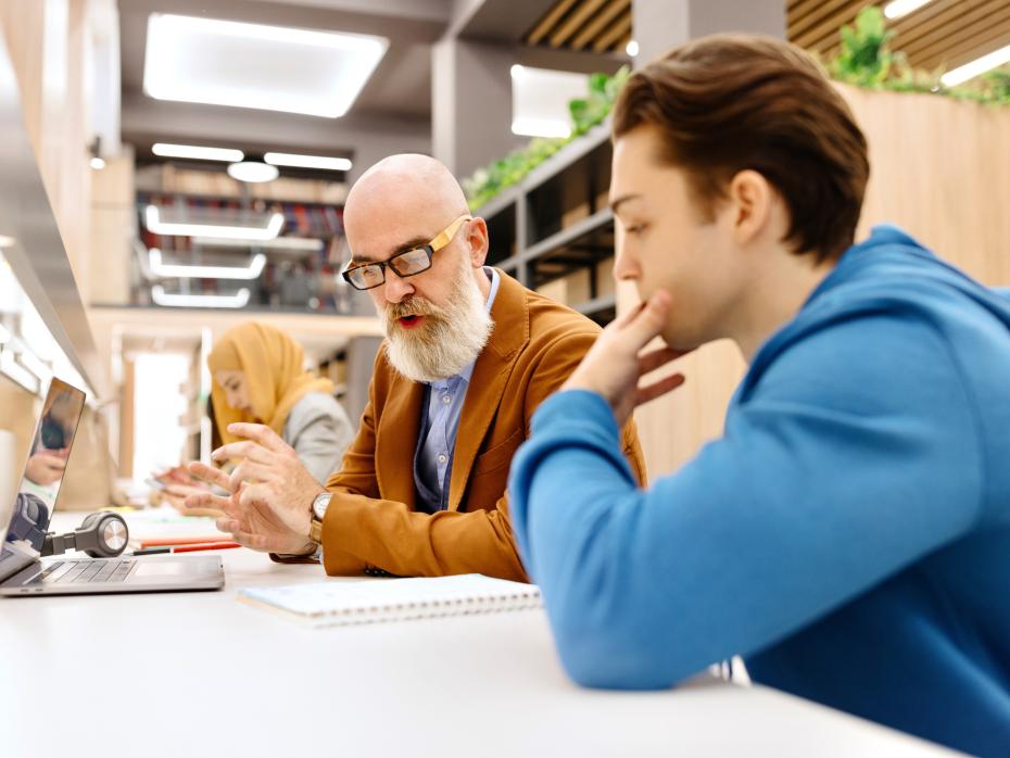 A lecturer talking to a student about their work.