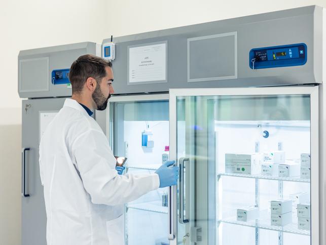 A scientist opens a freezer in a lab