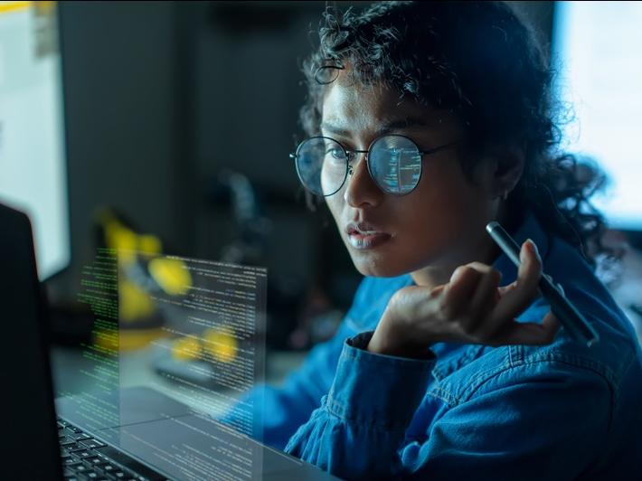 A programmer reviewing code on her desktop