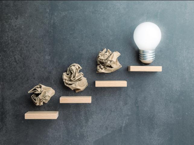 An illustration of screwed up bits of paper leading to a lightbulb moment