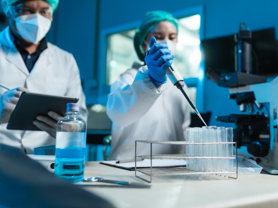 Two masked scientists fillin test tubes in a lab