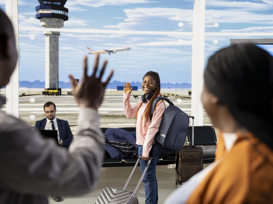 A young woman waves goodbye to family at an airport