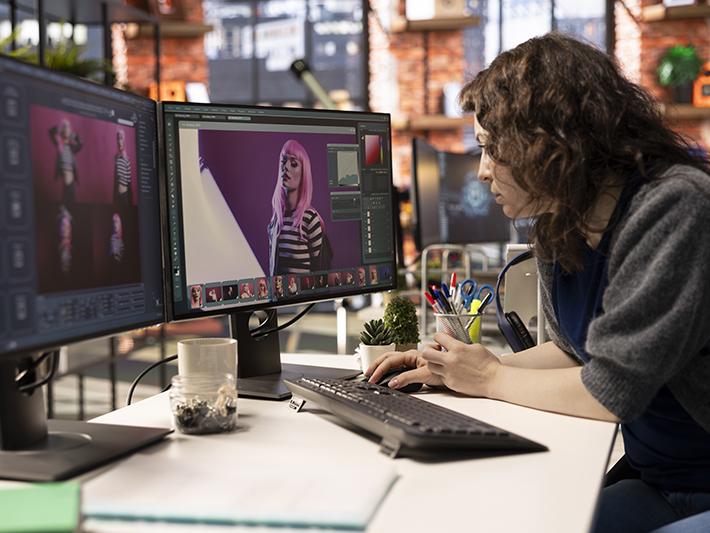 Female designer working with AI chat bot and an editing software - stock photo
