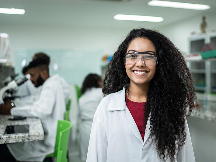 Female high school student in lab wearing a white coat