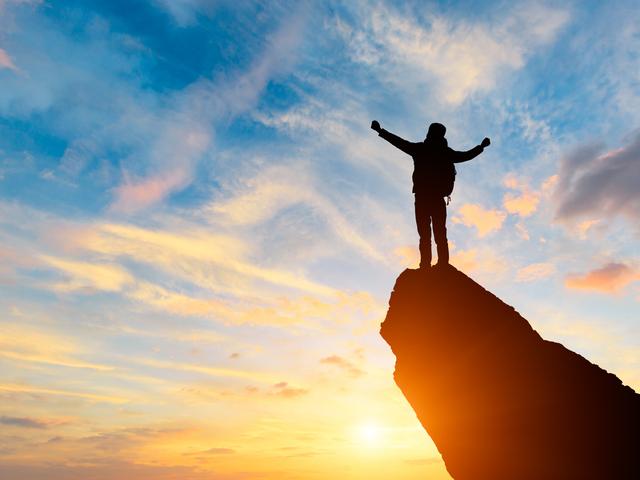 A figure stands on top of a mountain