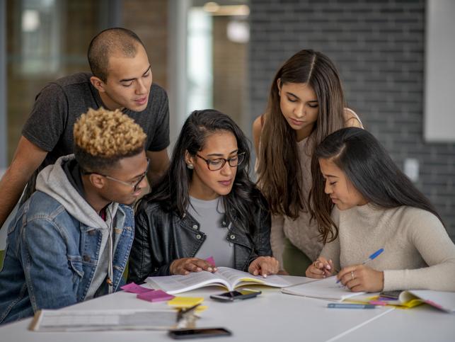 Students gather around a table to work together