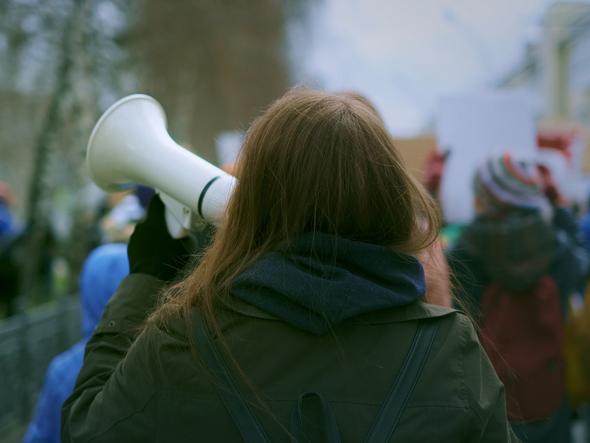 A young woman holds a megaphone at a protest