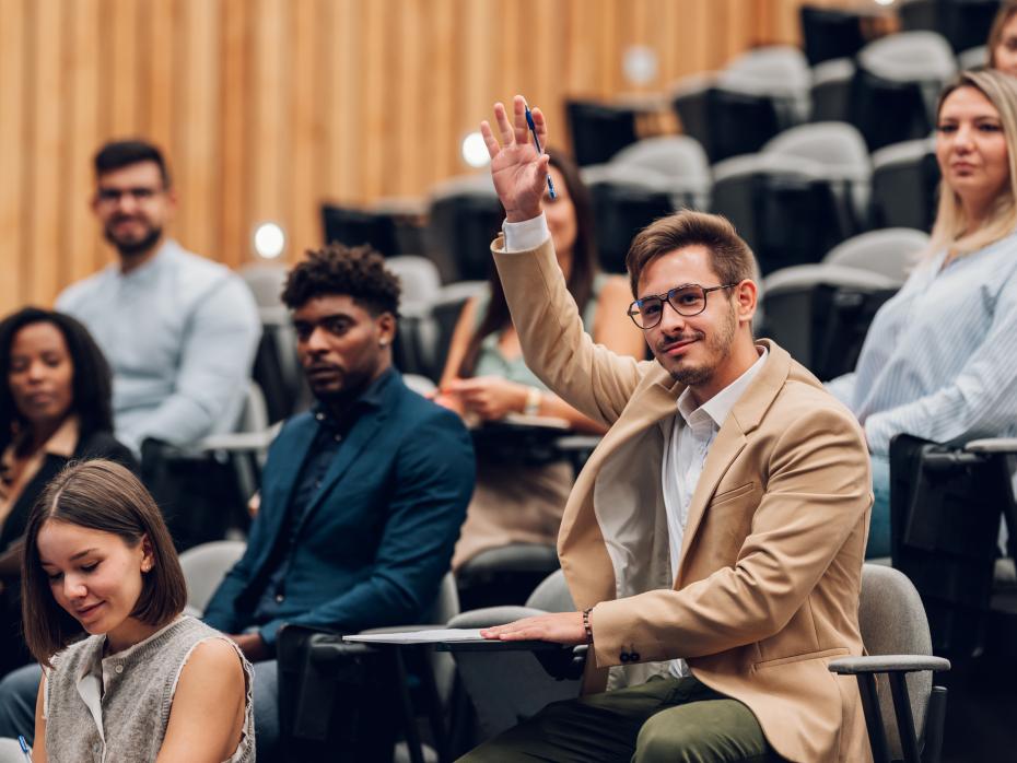 Student raising their hand to speak in a lecture
