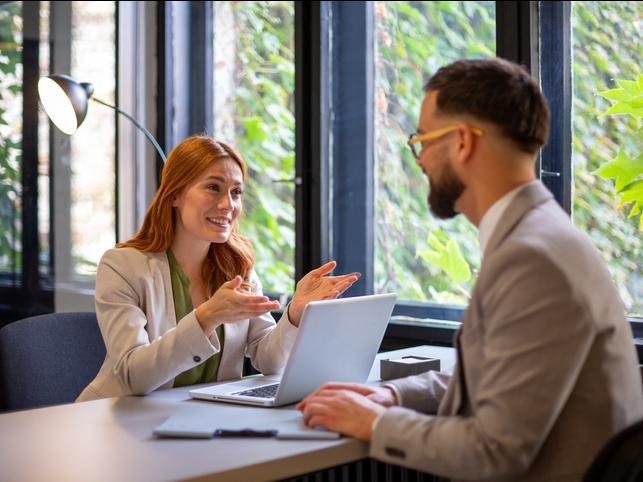Two people talk over a desk