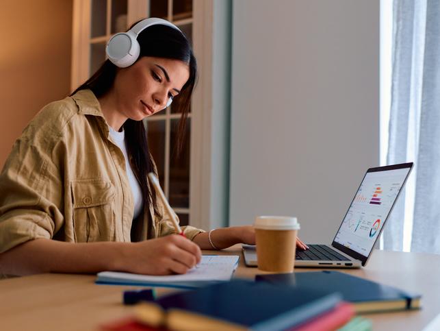 A student works at a laptop with headphones on