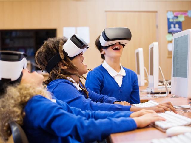 Three school children in class with VR headsets on