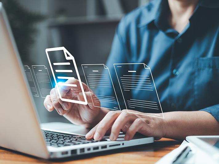 Male student working at laptop surrounded by images of documents
