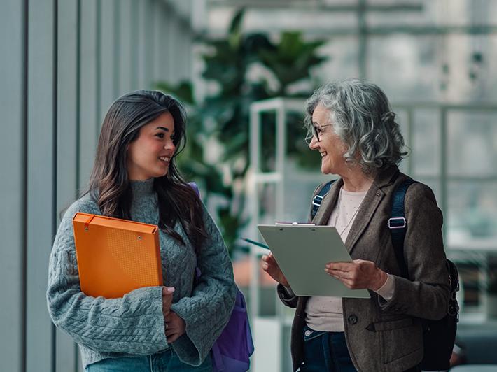 Young female university student meeting in all with older female supervisor
