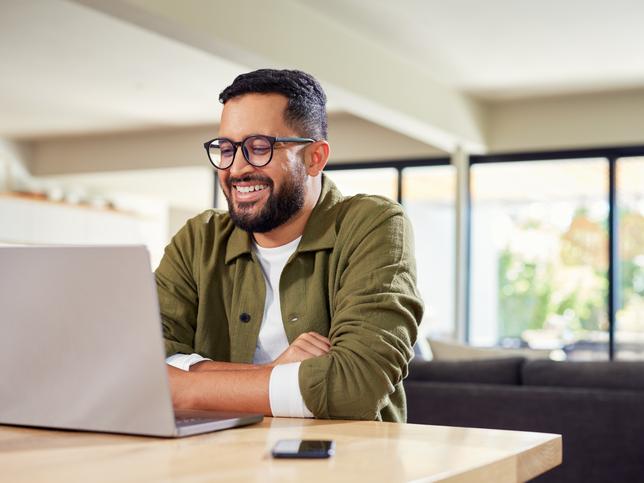 An online learner smiling at classmates on his laptop screen