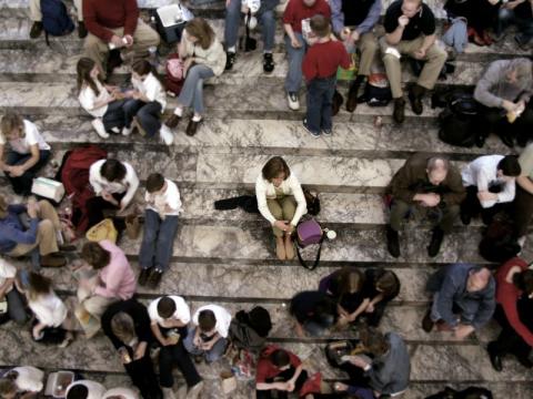 Image showing a woman sitting alone surrounded by chatting groups