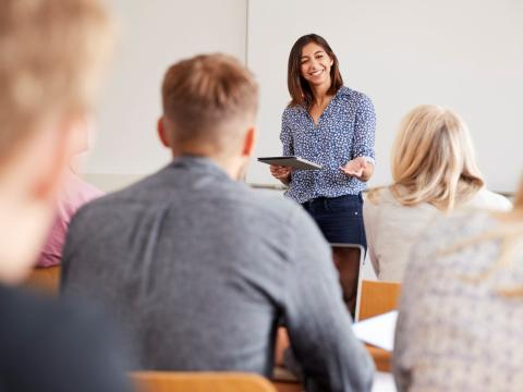 A female lecturer addressing a class of students