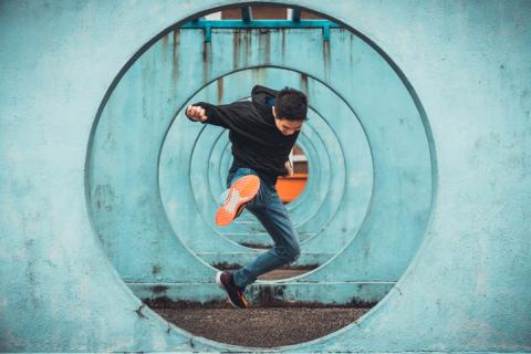 Young Asian man jumping through circular obstacles