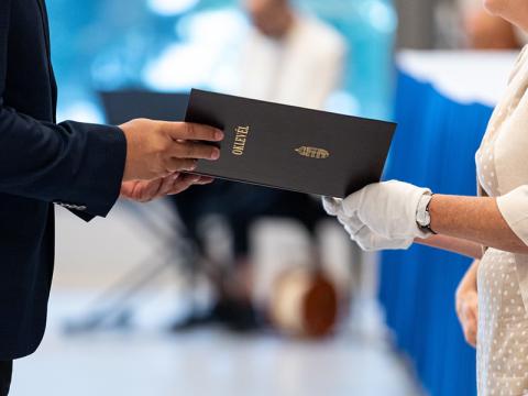 Cropped image of hands of PhD candidate receiving their certificate