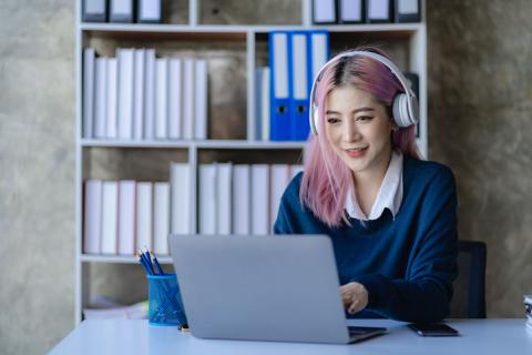 An Asian school girl working at a laptop