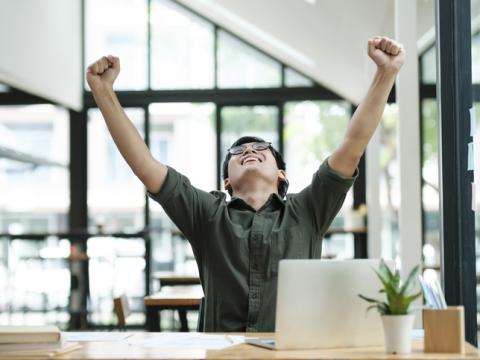 Asian male student happy with hands raised