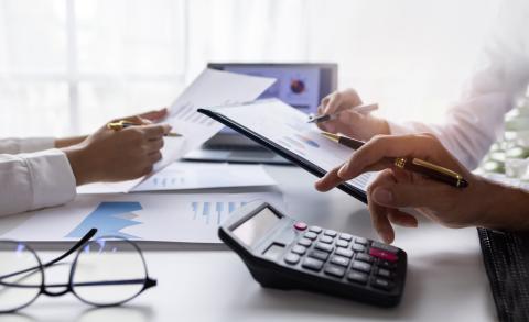 Calculator and hands writing down calculations on a desk