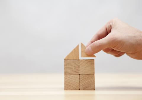 A hand adds the final building block to a small tower