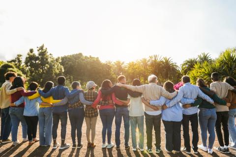 A row of students standing outside with their backs to the camera and their arms around each other 