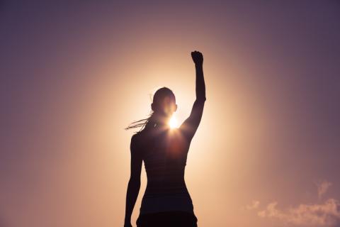 A sihouette of a woman raising her fist in the air