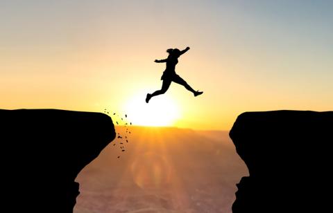 A woman jumps from one rock ledge to another